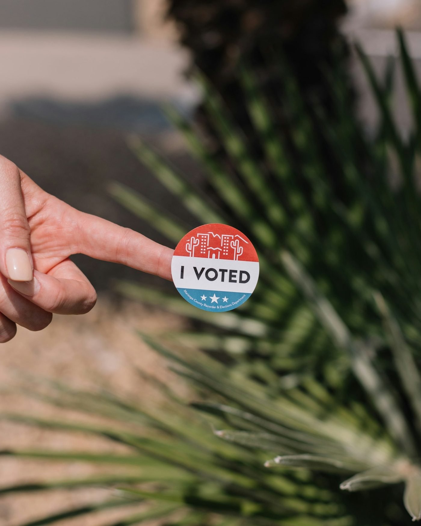 Hand holding an I Voted pin outdoors in Florida
