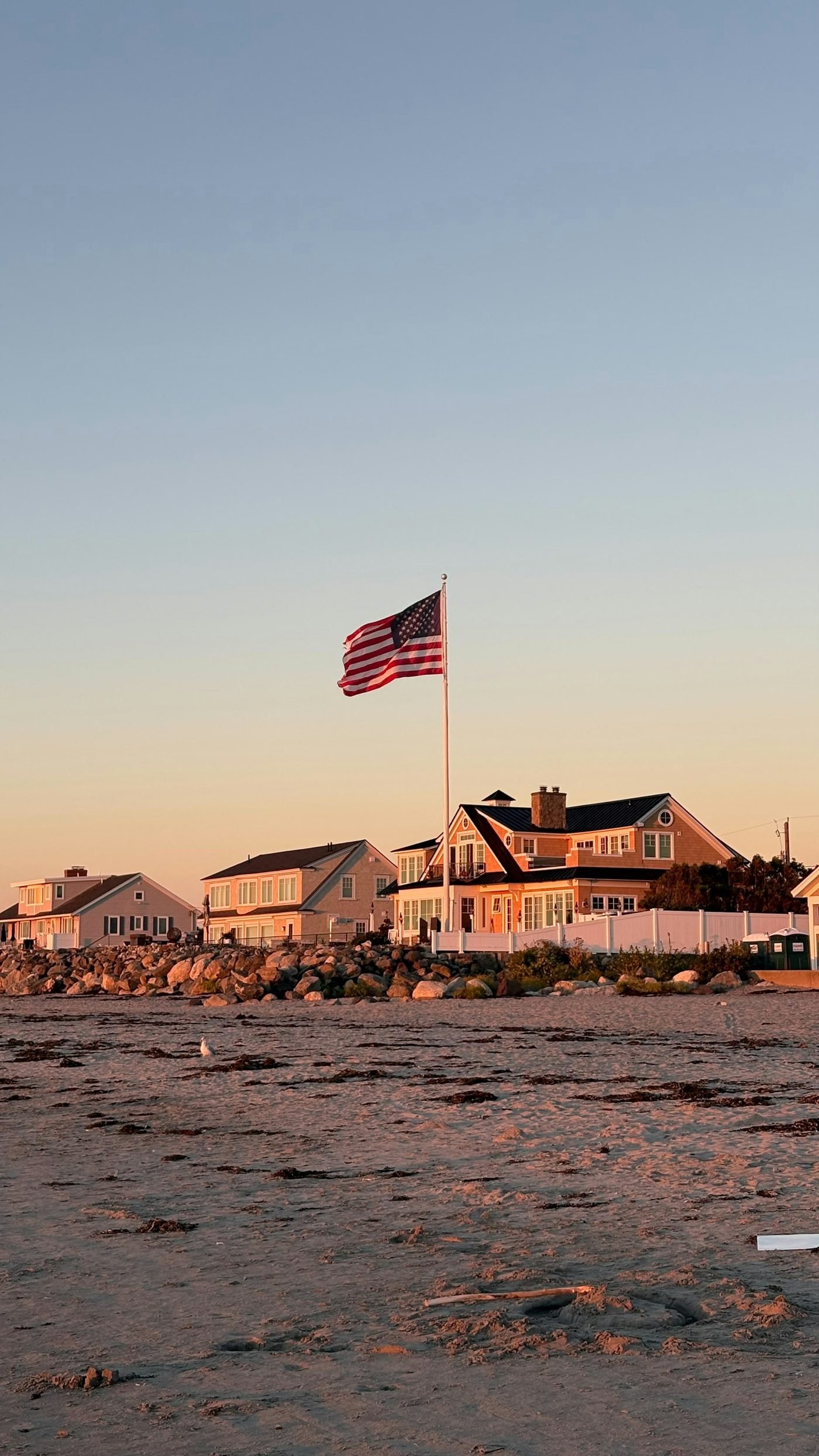 American flag flying over waterfront family homes at sunset